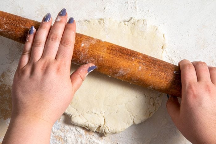 A person Rolling the dough with a roller