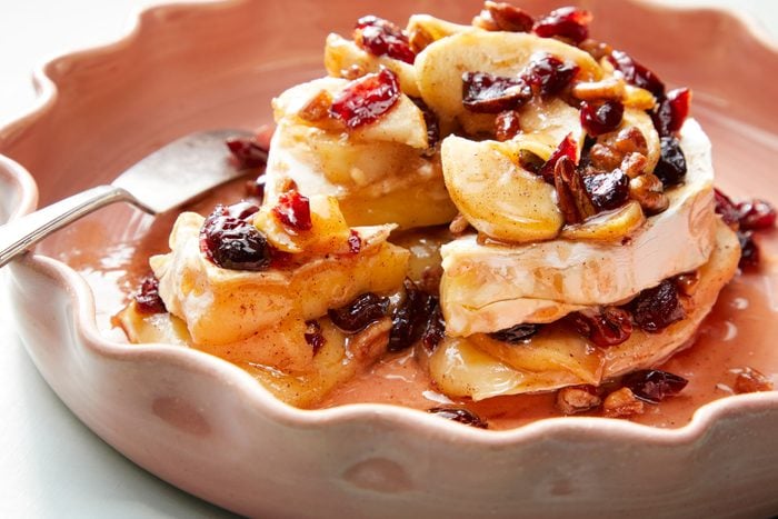 Apple Pecan Baked Brie served in a bowl adorned with a variety of fruits and nuts