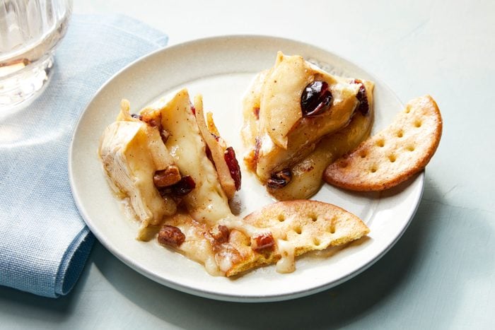 Apple-Pecan Baked Brie with cheese and crackers on a plate