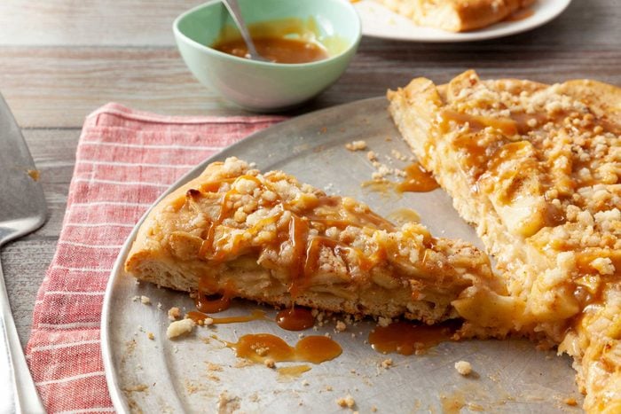 Apple pizza slices topped with caramel drizzle on a crispy crust