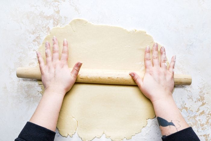 Rolling the dough with a roller on a floured surface