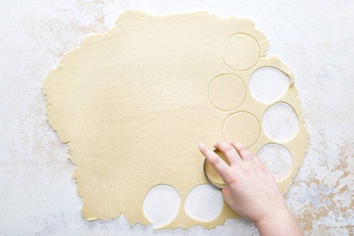 Cutting the dough round shaped with a cookie cutter.