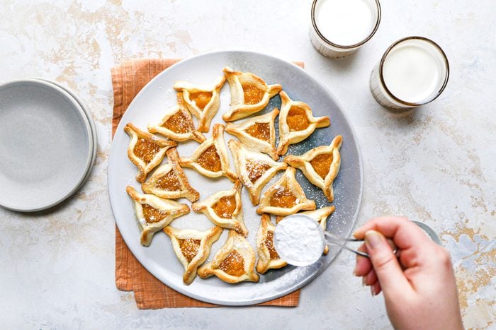 Dusting the confectioners' sugarApricot Filled Triangles served on a plate.