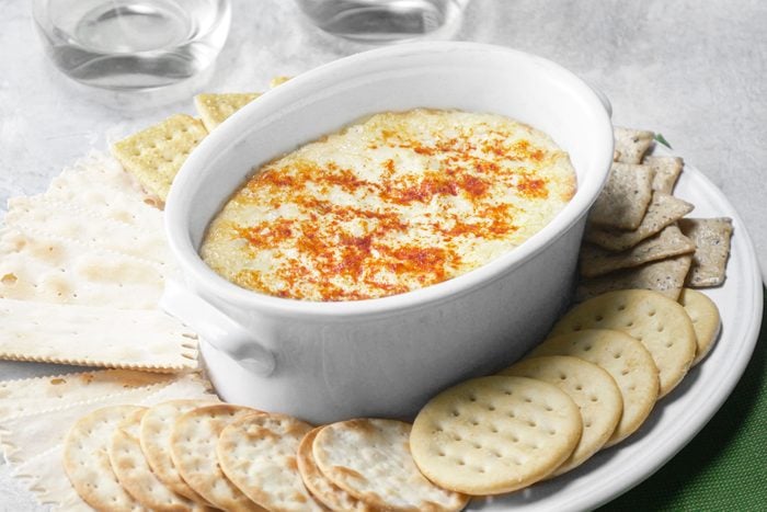 Artichoke Dip and crackers in a large white place on a table