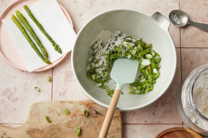 combining Asparagus and flour in a large bowl using a spatula