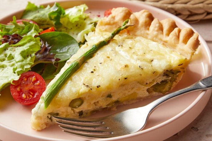 Asparagus Quiche in a plate with vegetables and fork 