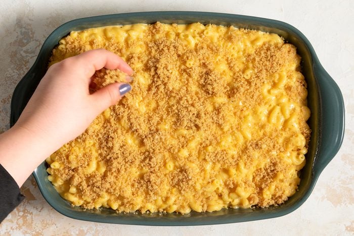 spreading bread crumbs on Baked Mac And Cheese