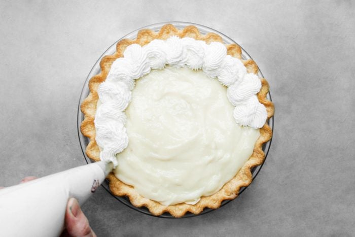 Spreading whipped cream on Pie