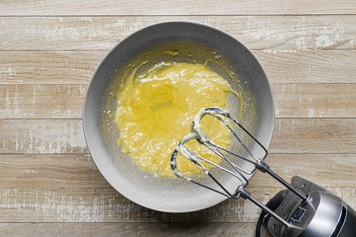 A bowl with eggs mixture with a whisk.