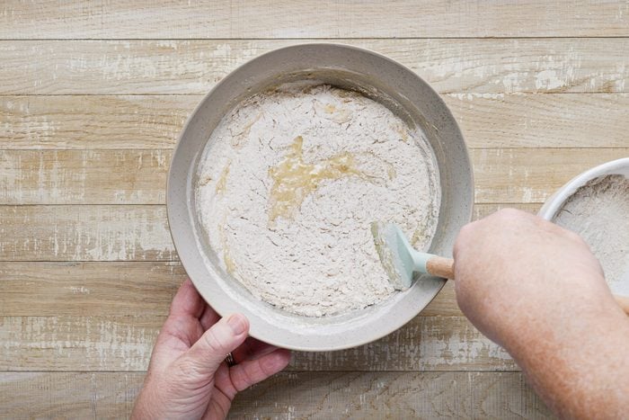 A person mixing flours in a bowl.