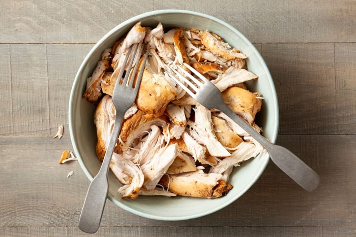 Shredded Chicken with Two Forks in A Large Bowl on Wooden Surface