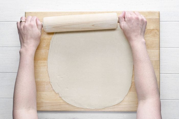 Preparing the dough with a roller on a wooden tray