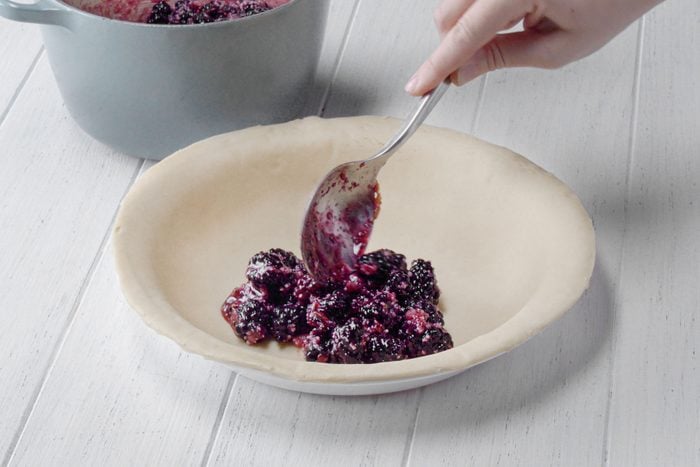 Filling the pie crust with Blackberry mixture with a spoon