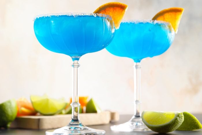 Blue Margarita garnished with sliced fruit on rim of the glass