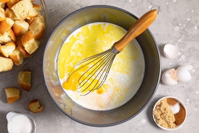eggs, egg yolks and milk in a large bowl ready to mix by a whisk egg beater