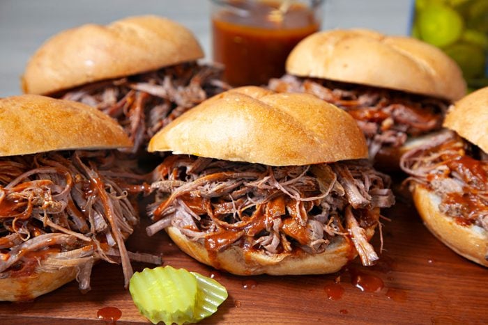 Delicious Pulled Brisket Sandwiches arranged on a wooden platter with Worcestershire sauce