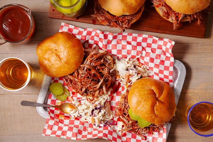 Tempting Pulled Brisket Sandwiches arranged on a wooden platter with Worcestershire sauce and beer
