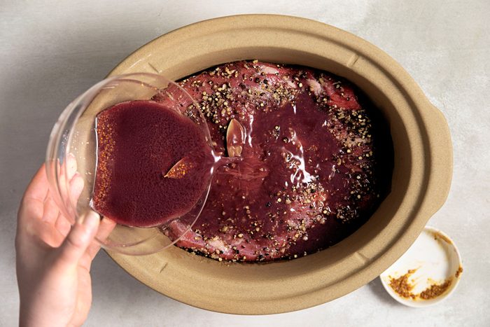 Pouring the red wine mixture over brisket