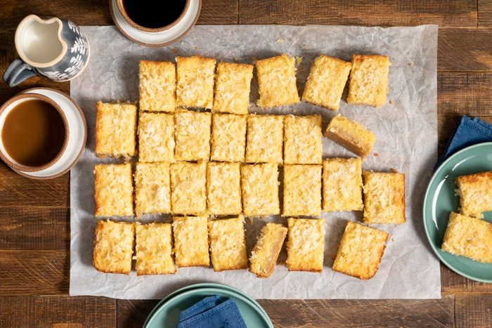 Buttery Coconut Bars served on a baking sheet on a wooden surface