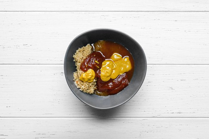 Brown sugar, ketchup, vinegar and mustard mixed in a small bowl on a wooden table