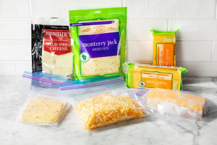 Packages of cheese and the ways to freeze cheese shown on a kitchen counter