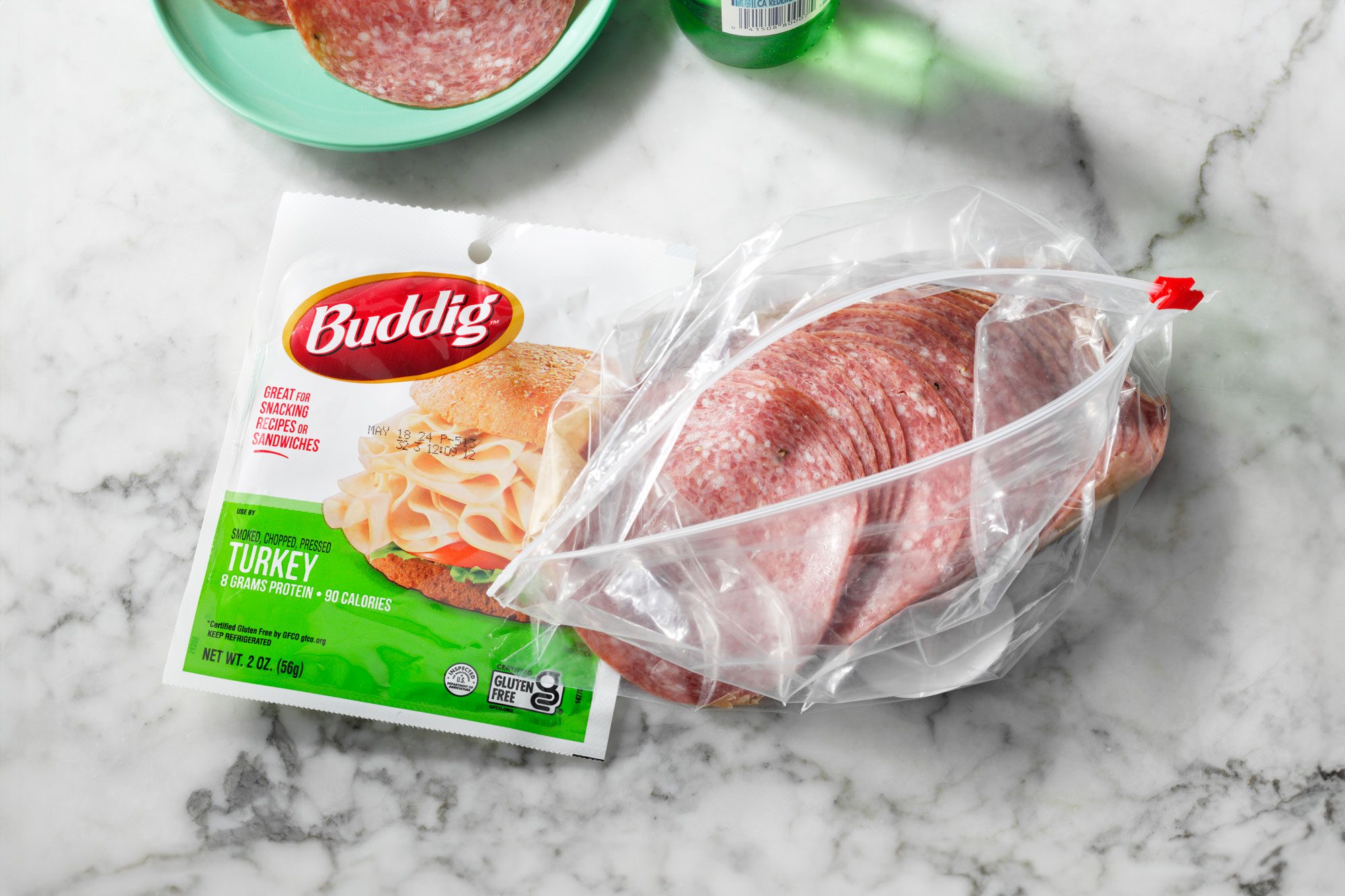 Pre-packaged and deli counter lunch meat packages on a marble countertop