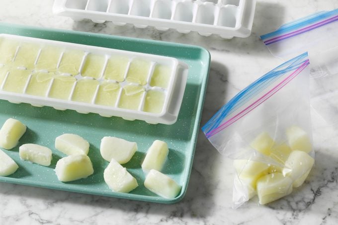 Frozen cubes of milk being transferred from the ice cube trays into freezer bags