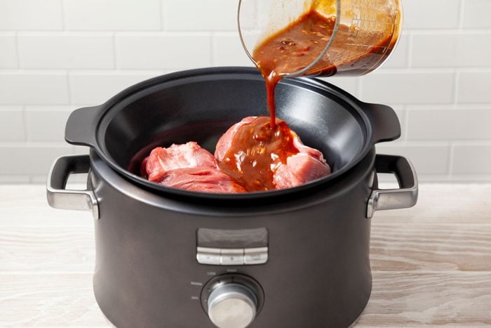 Pouring the sauce over the meat in a slow cooker