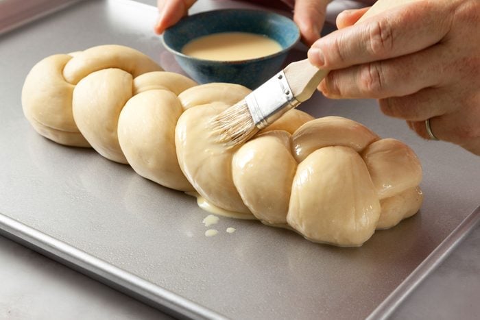 Brushing the braided dough on baking sheet