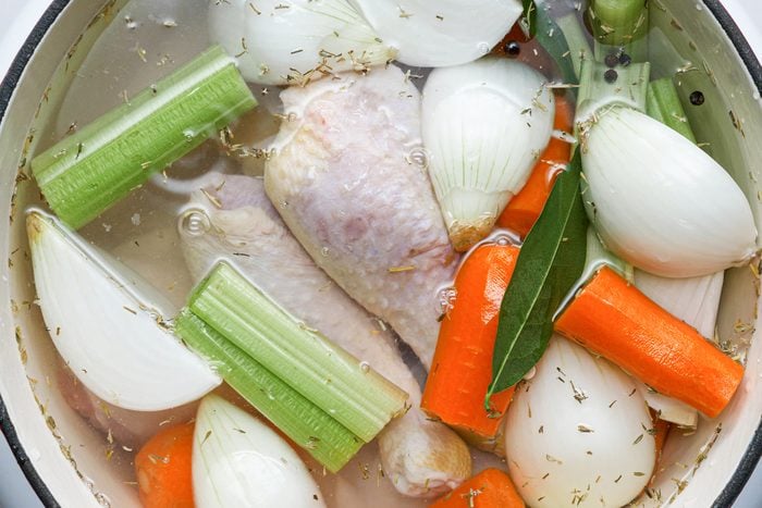 Chicken pieces, vegetables with herbs and other ingredients boiling in the dutch oven