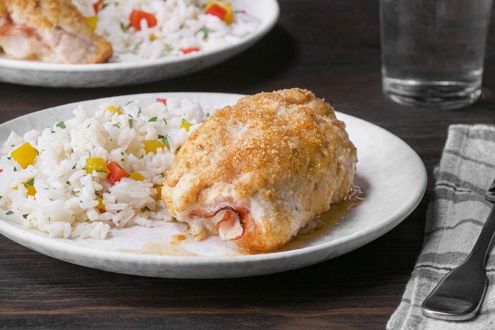 Chicken Cordon Bleu Served with Rice on a White Plate on Wooden Surface