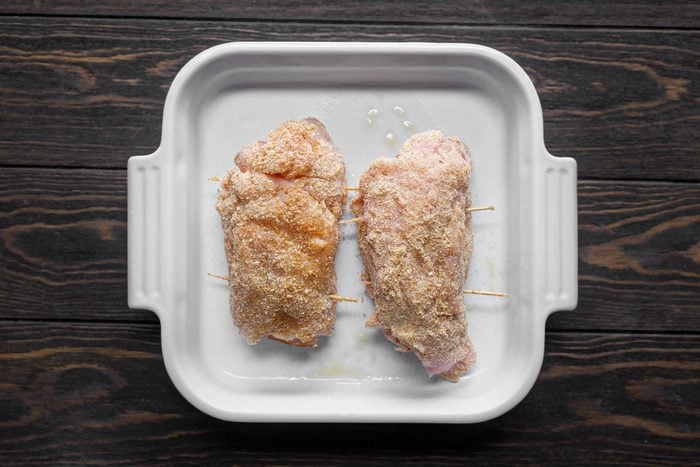 Raw Chicken Cordon Bleu in a square baking dish on Wooden Surface