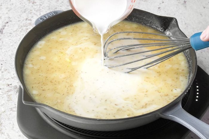 Stirring in the broth and milk in a large skillet with a spatula.
