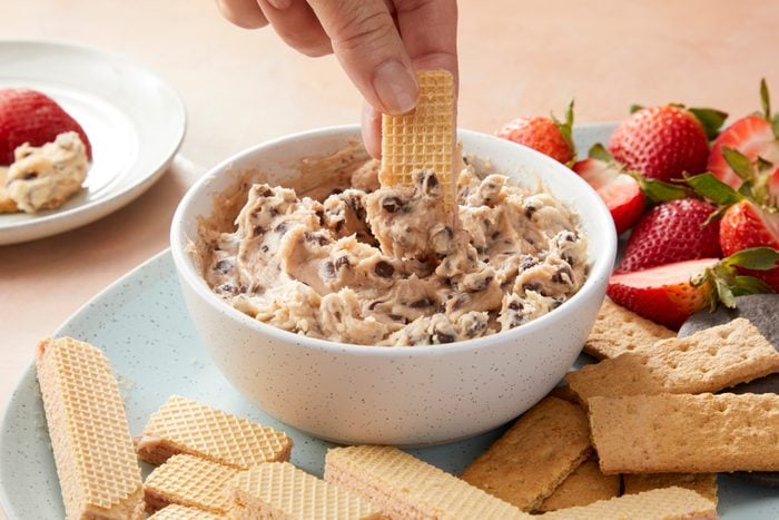 A person dipping a cracker into a bowl of chocolate chip dip