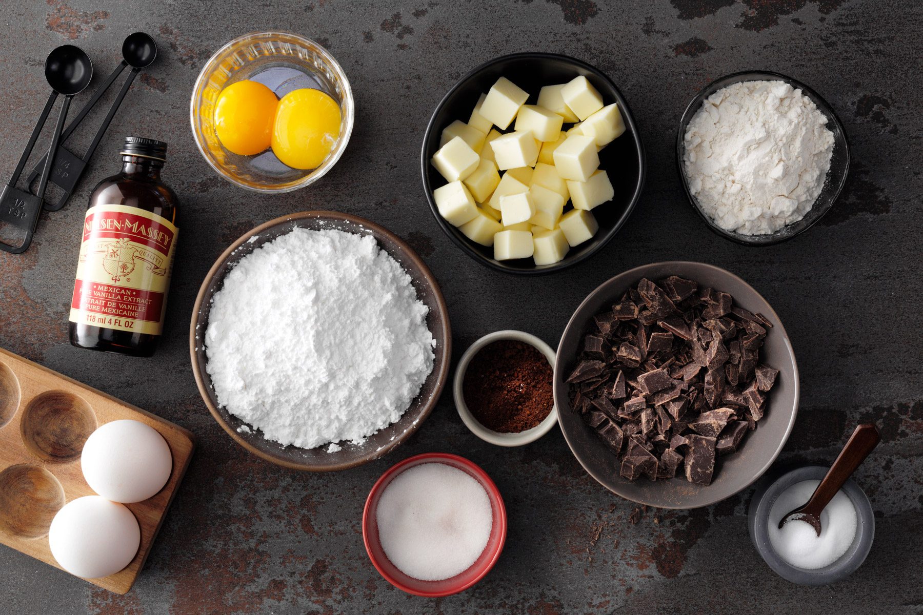 An ingredients for a chocolate lava cake, including flour, cocoa powder, eggs, sugar, and butter.