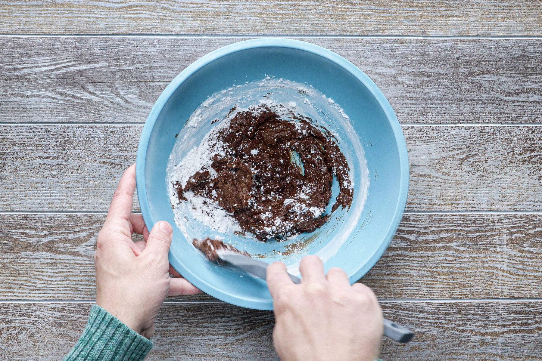 A person mixing chocolate and flour in a bowl