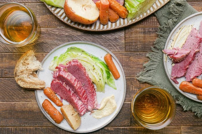 Corned Beef And Cabbage served with bread in a plate along with beverage