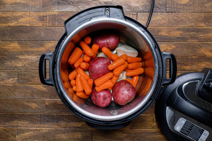 Vegetables in a slow cooker placed on a wooden surface