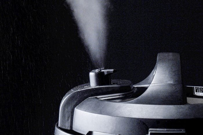 Steam getting out of the pressure cooker placed against a black background