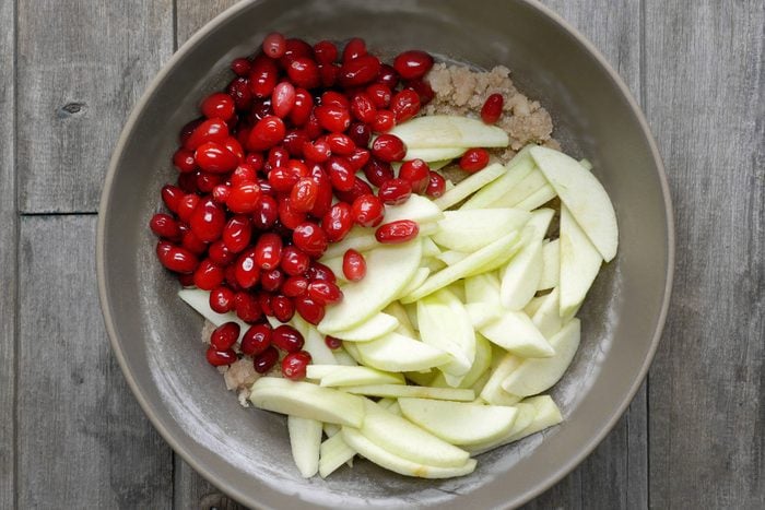 Apples and cranberries and sugar mixture in a large bowl