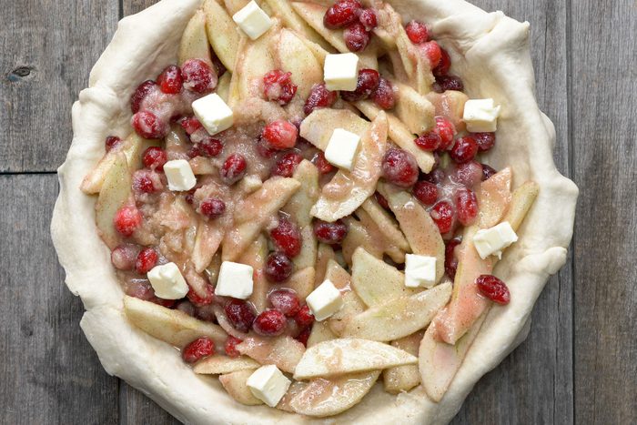 Cranberry Apple Pie filling in a pie crust placed on a wooden table