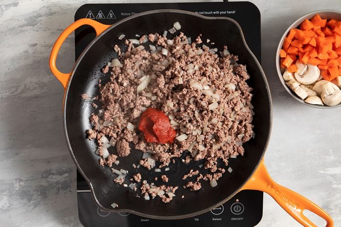 Tomato paste added in meat mixture in skillet