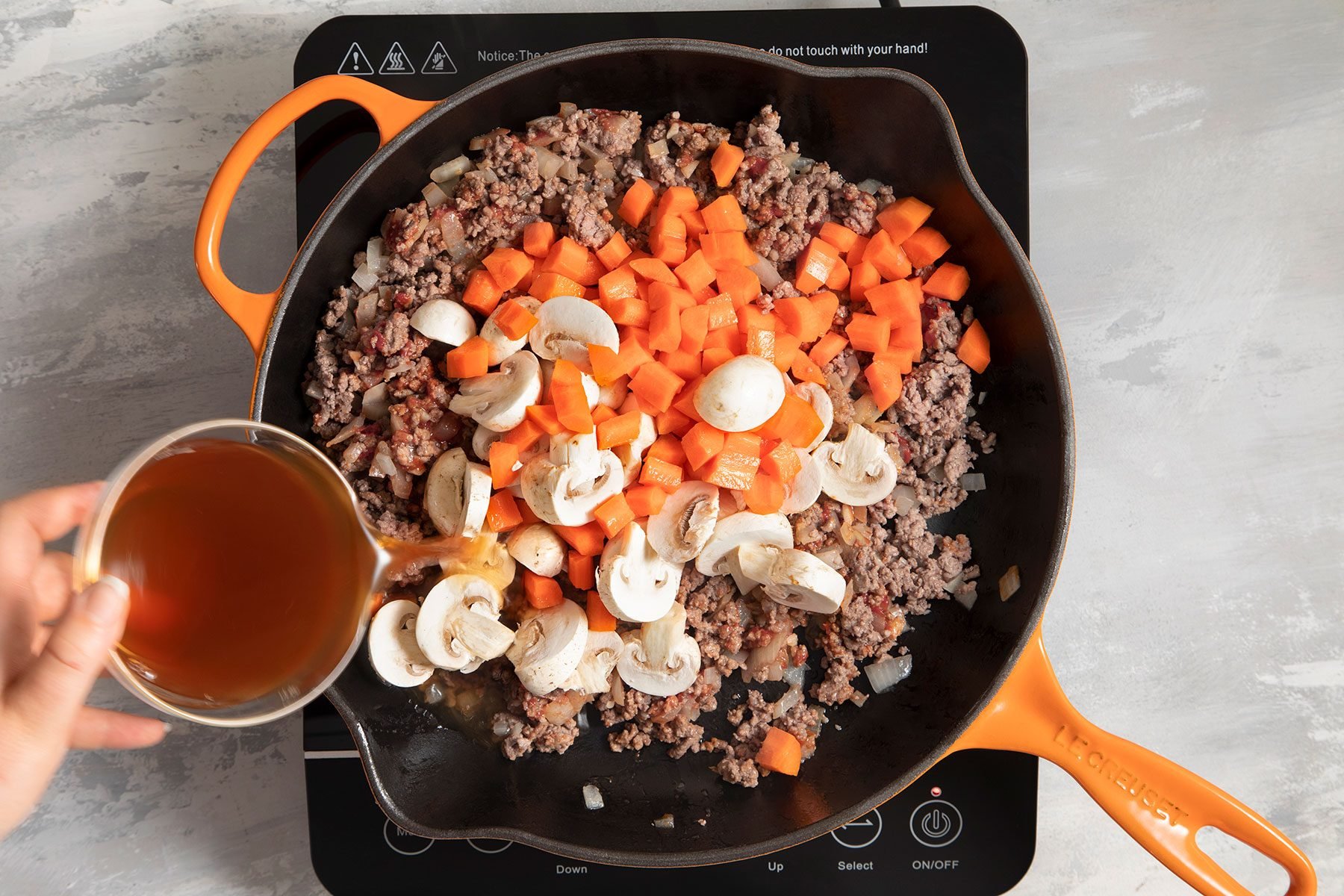 Carrots, Mushrooms and wine added in meat mixture cooking in skillet