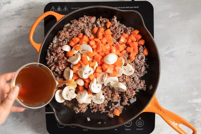Carrots, Mushrooms and wine added in meat mixture cooking in skillet