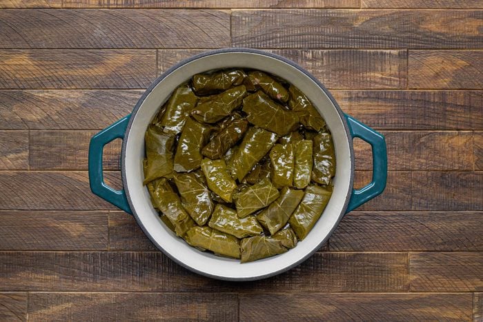 Rolled grape leaves with beef mixture inside arranged in a large pan