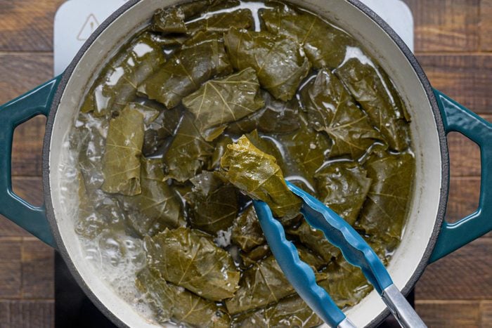 Removing the dolmades using tongs from the dutch oven