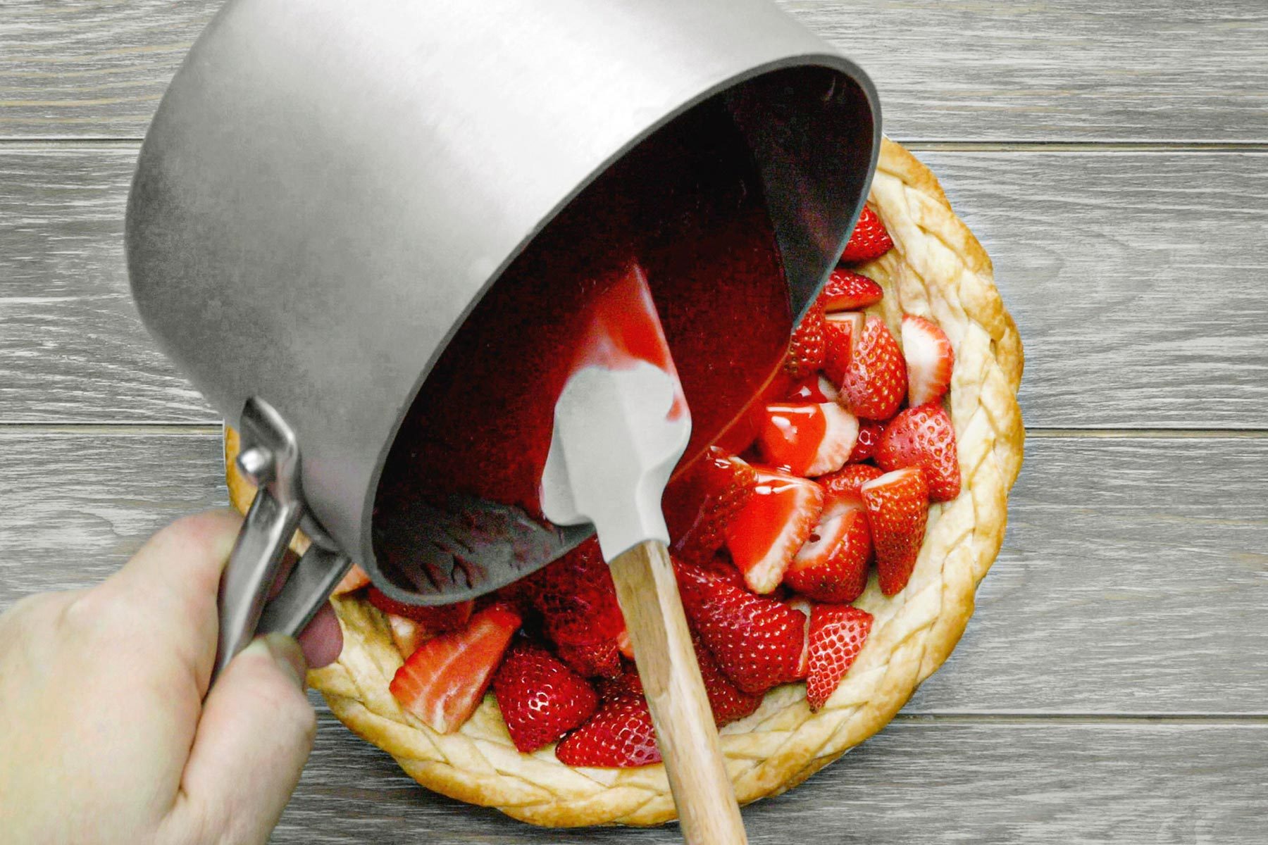 Pouring gelatin mixture over strawberries