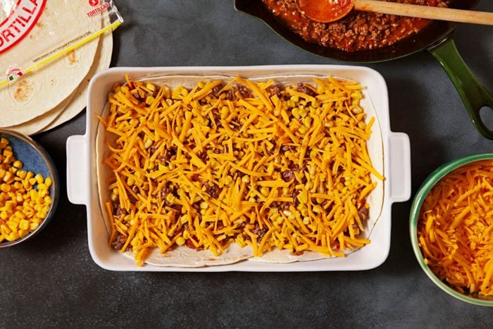 Layers of Tortillas, meat and cheese in a large pan 