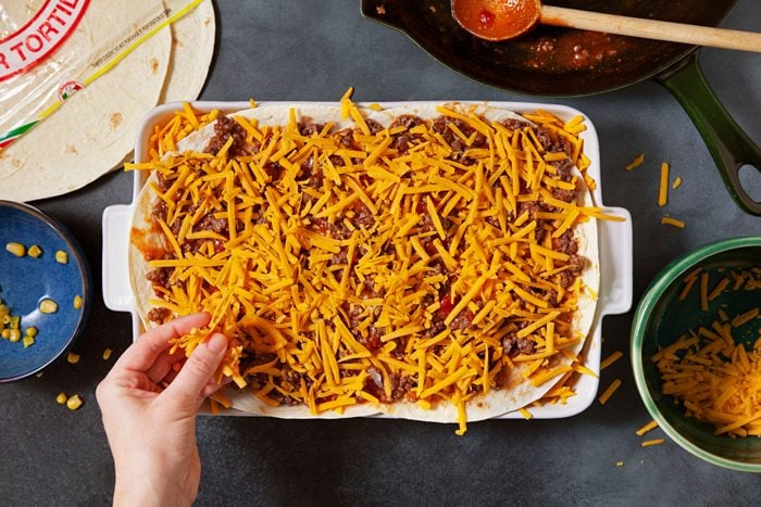 Layers of Tortillas, meat and cheese in a large pan