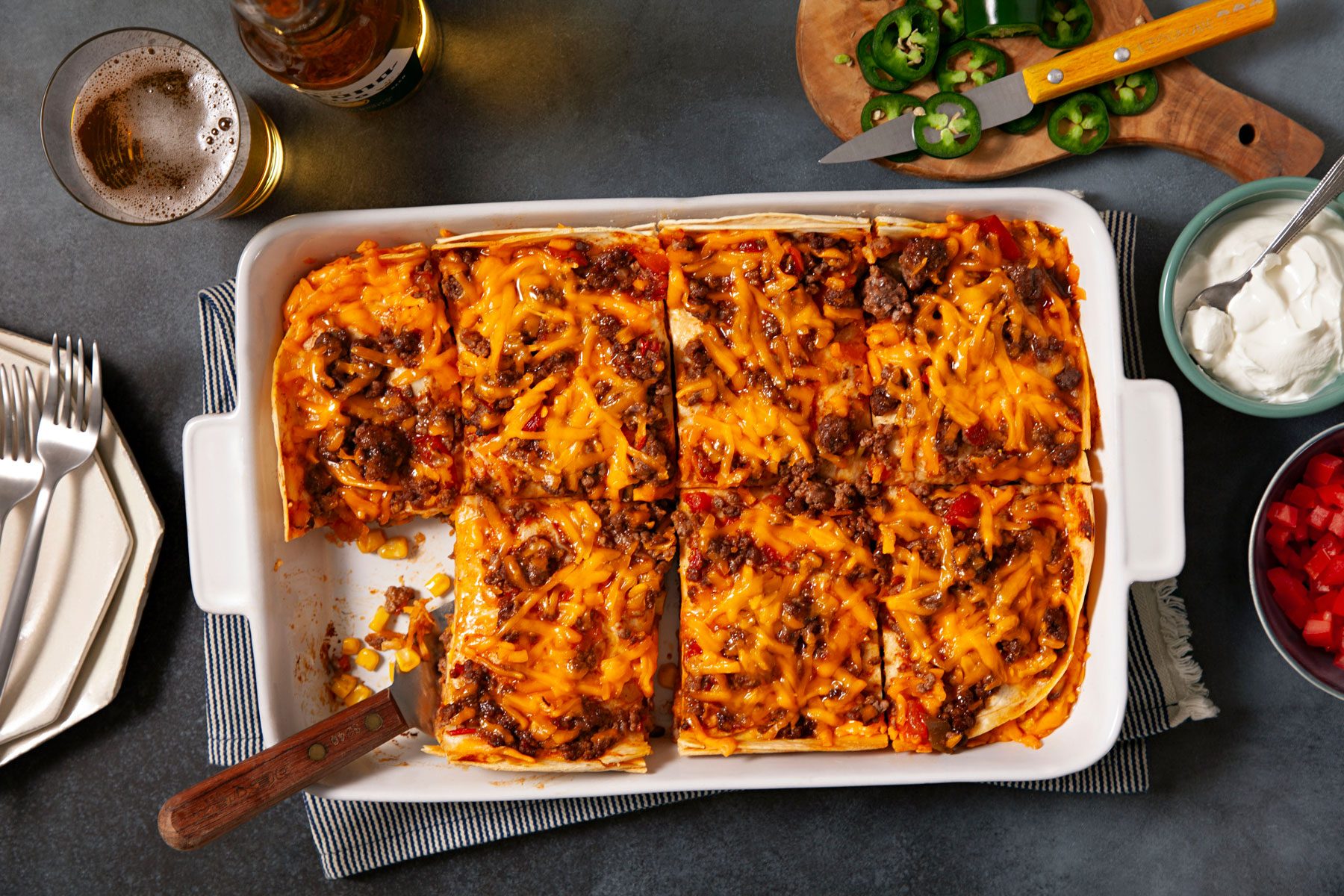 Baked Enchilada Casserole served in a large baking pan with a beverage. 